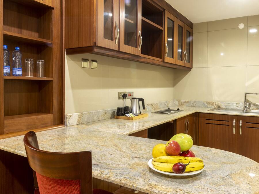 A kitchen with granite countertops, wooden cabinets, and a fruit bowl on the counter.