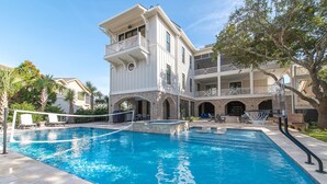 A multi-story hotel with a swimming pool, outdoor seating, and a basketball court.
