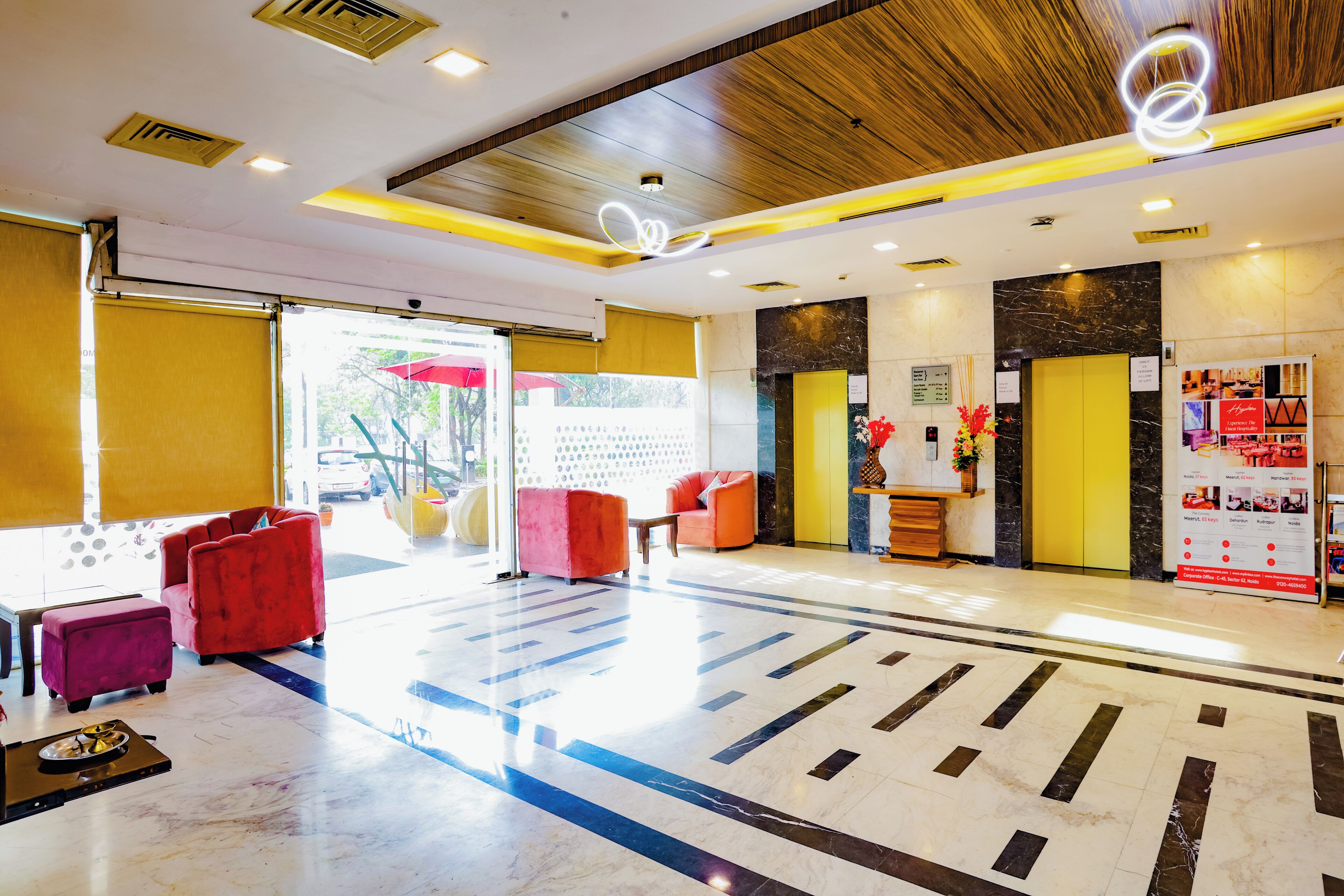 A modern lobby with a marble floor, red seating, and a reception desk.