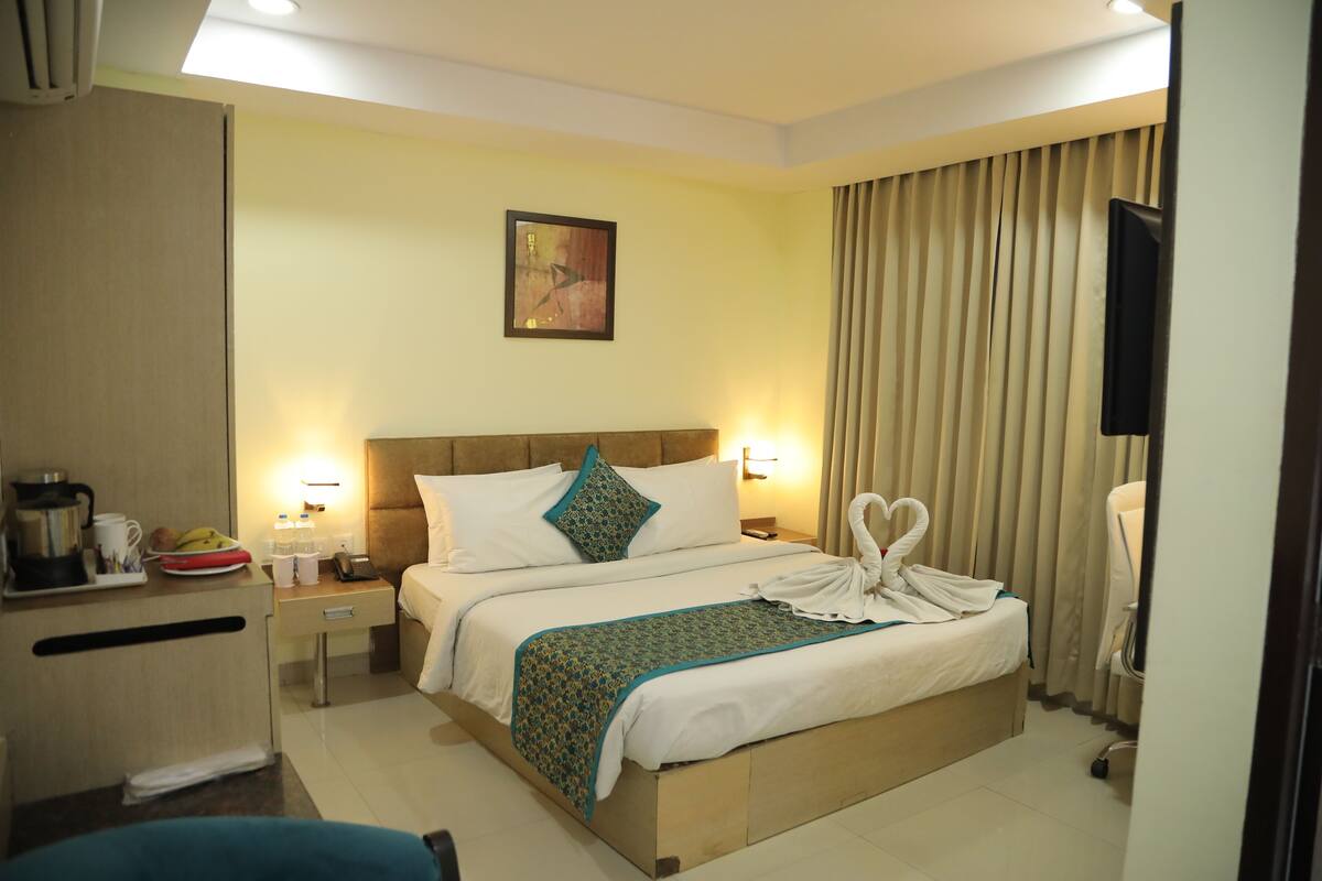 A hotel room with a bed, bedside tables, a desk, and a television.