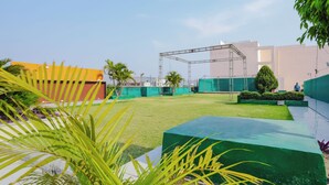 Un patio con macetas verdes, una estructura metálica y un edificio de techo plano.
