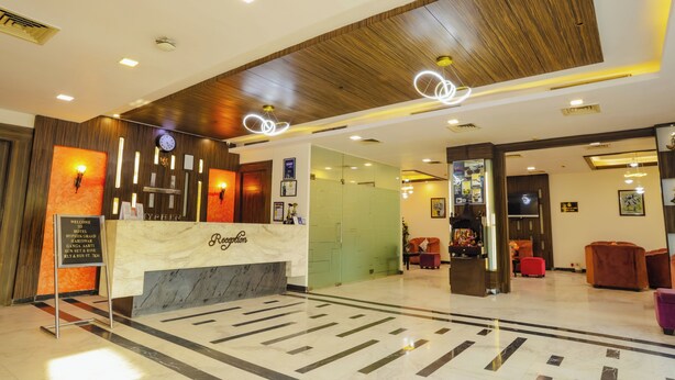 Zona de recepción de un hotel con mostrador de mármol, techo de madera y luminarias modernas.