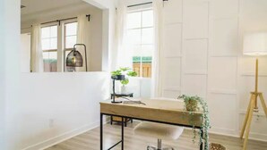 A modern room with a wooden desk, a white chair, a lamp, and a potted plant.