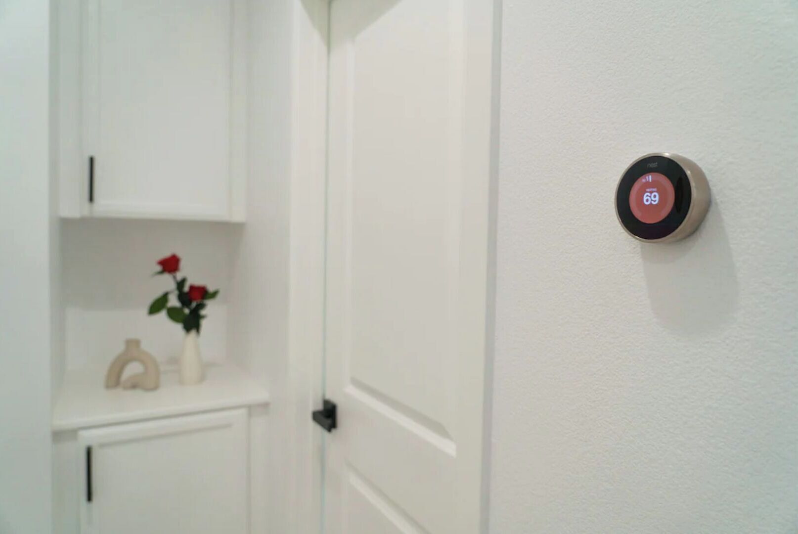 A white door with a Nest thermostat displaying a temperature of 69°F.