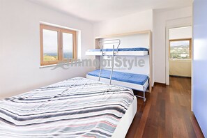 Une chambre avec un lit superposé, une fenêtre donnant sur un beau paysage et un plancher en bois.
