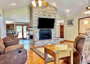 A living room with a stone fireplace, a flat-screen TV, and a large sofa.