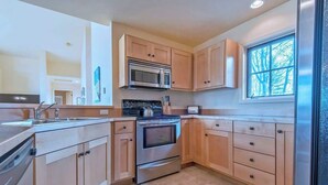 A modern kitchen with light wood cabinets, stainless steel appliances, and a large window providing natural light. - Teton Homestead: Bunkbeds, Private Deck, Targhee (Driggs)