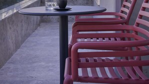 A balcony with a table and two chairs, overlooking a hillside with buildings. - The Social Athens Hotel, a member of Radisson Individuals (Athens)