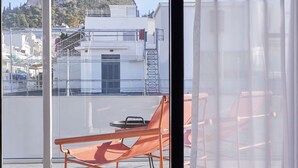 A balcony with a view of a hill, a chair, and a table. - The Social Athens Hotel, a member of Radisson Individuals (Athens)