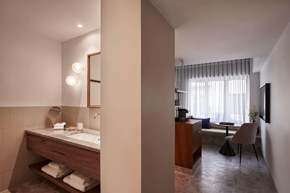 A modern bathroom with a vanity, mirror, and built-in shelves.