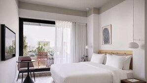 A hotel room with a bed, a small table, a chair, a nightstand, and a window with curtains. - The Social Athens Hotel, a member of Radisson Individuals (Athens)