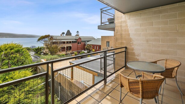 A balcony with a view of the sea, a table, and two wicker chairs. - Apartment 30 Pacific Apartments (Lorne)