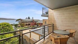 Enjoy the serene coastal views from this balcony with a table and two chairs.