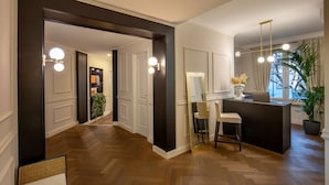 A modern hotel lobby with a wooden floor, a reception desk, a seating area, and a large mirror. - Daplace - Corso Monforte Suites (Milan)