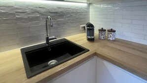 Een moderne keuken met een zwarte spoelbak, witte kasten en een achterwand van steen.