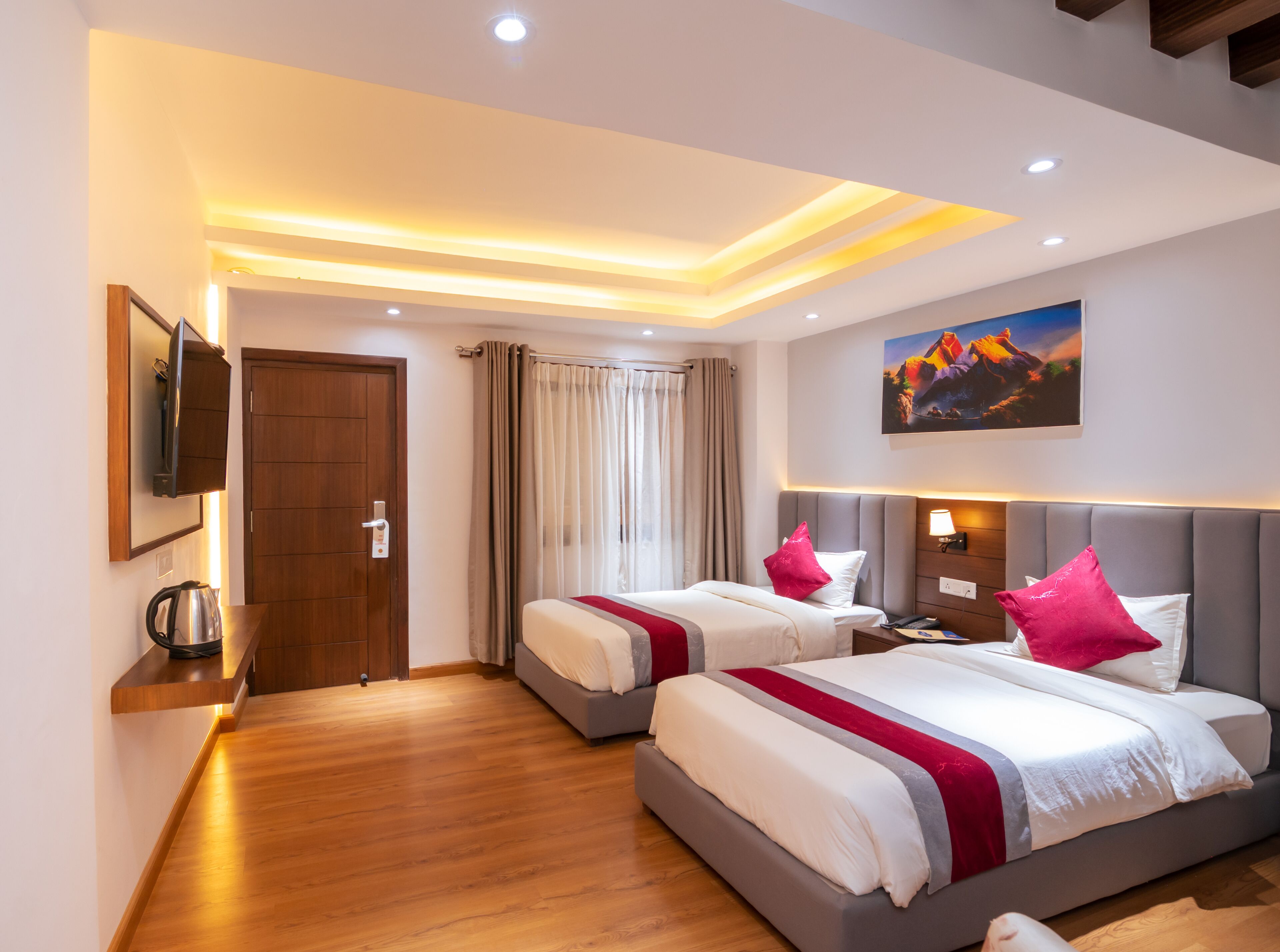 Habitación de hotel con dos camas, televisión, un cuadro y suelo de madera.