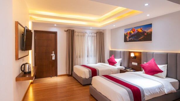 A hotel room with two beds, a TV, a painting, and a wooden floor. - Hotel Ama-La, The Heart of Comfort in Thamel (Kathmandu)
