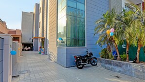 Un bâtiment moderne avec de grandes fenêtres, une moto garée devant et un palmier.
