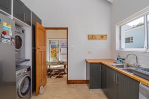 A modern kitchen with grey cabinets, a wooden countertop, and a view of a beach through a glass door.