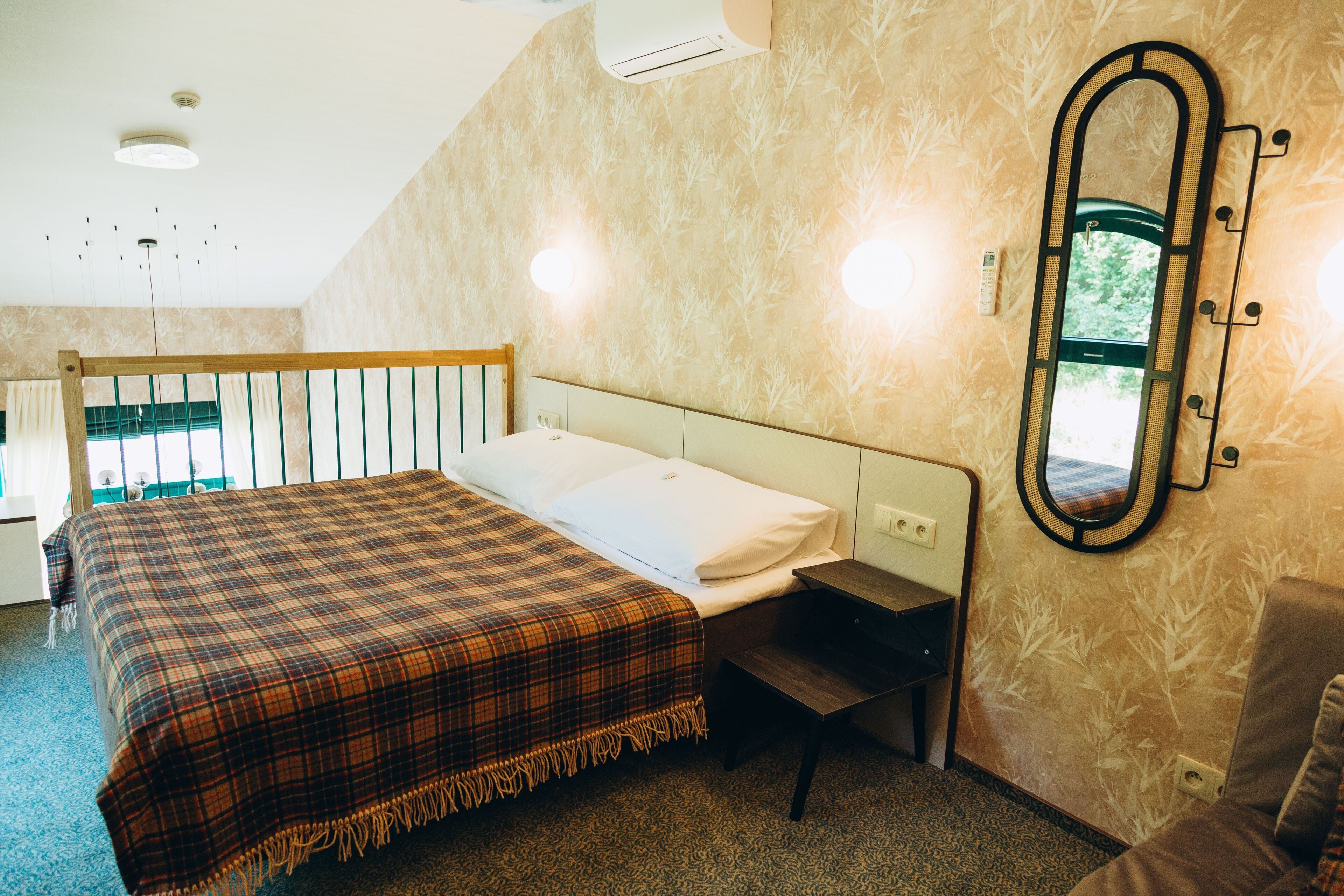 Un dormitorio con cama, mesita de noche, espejo y ventana.