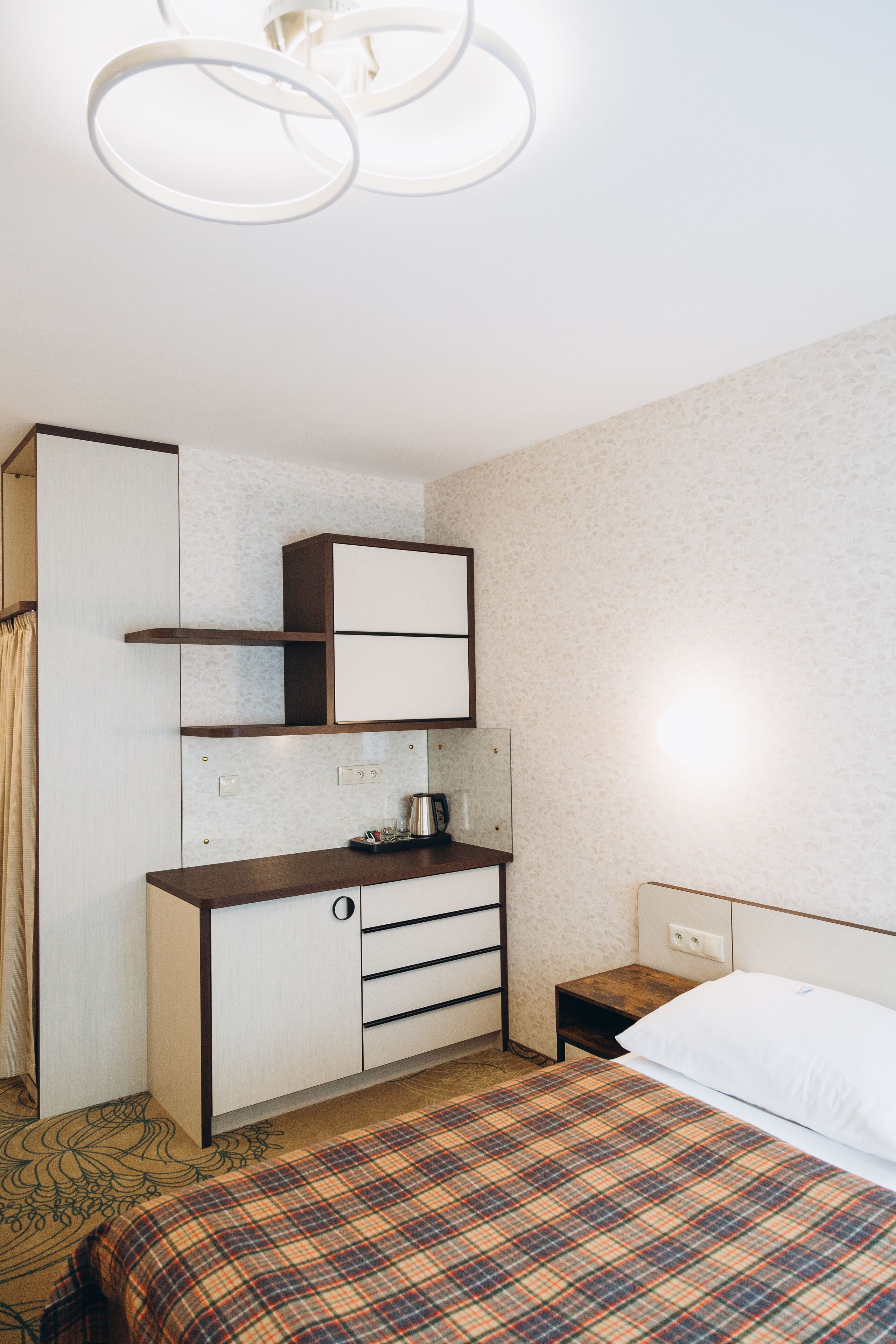 A bedroom with a bed, a wardrobe, a desk, and a nightstand.