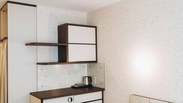 A bedroom with a bed, a wardrobe, a desk, and a nightstand.