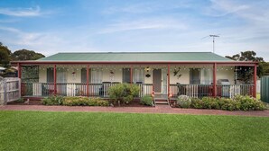 A two-story building with a green roof, a covered porch with string lights, and a fenced yard. - Cross Rhodes in Wimbledon Heights (Wimbledon Heights)