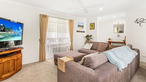 A living room with a flat-screen TV, a wooden entertainment unit, a sofa, and a coffee table. - Cross Rhodes in Wimbledon Heights (Wimbledon Heights)