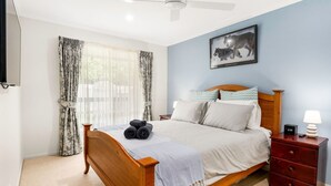 A bedroom with a wooden bed, a nightstand with a lamp, and a painting of a wolf on the wall. - Cross Rhodes in Wimbledon Heights (Wimbledon Heights)