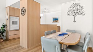 A modern kitchen with wooden cabinets, a built-in oven, and a clock.
