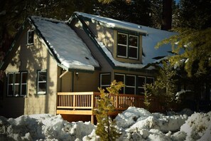 Situated in a wooded area, this charming house features a front porch, double-hung windows, and a chimney.
