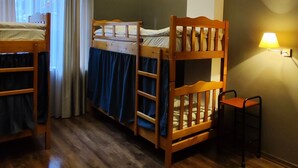 Een kamer met twee stapelbedden, een bureau en een stoel.