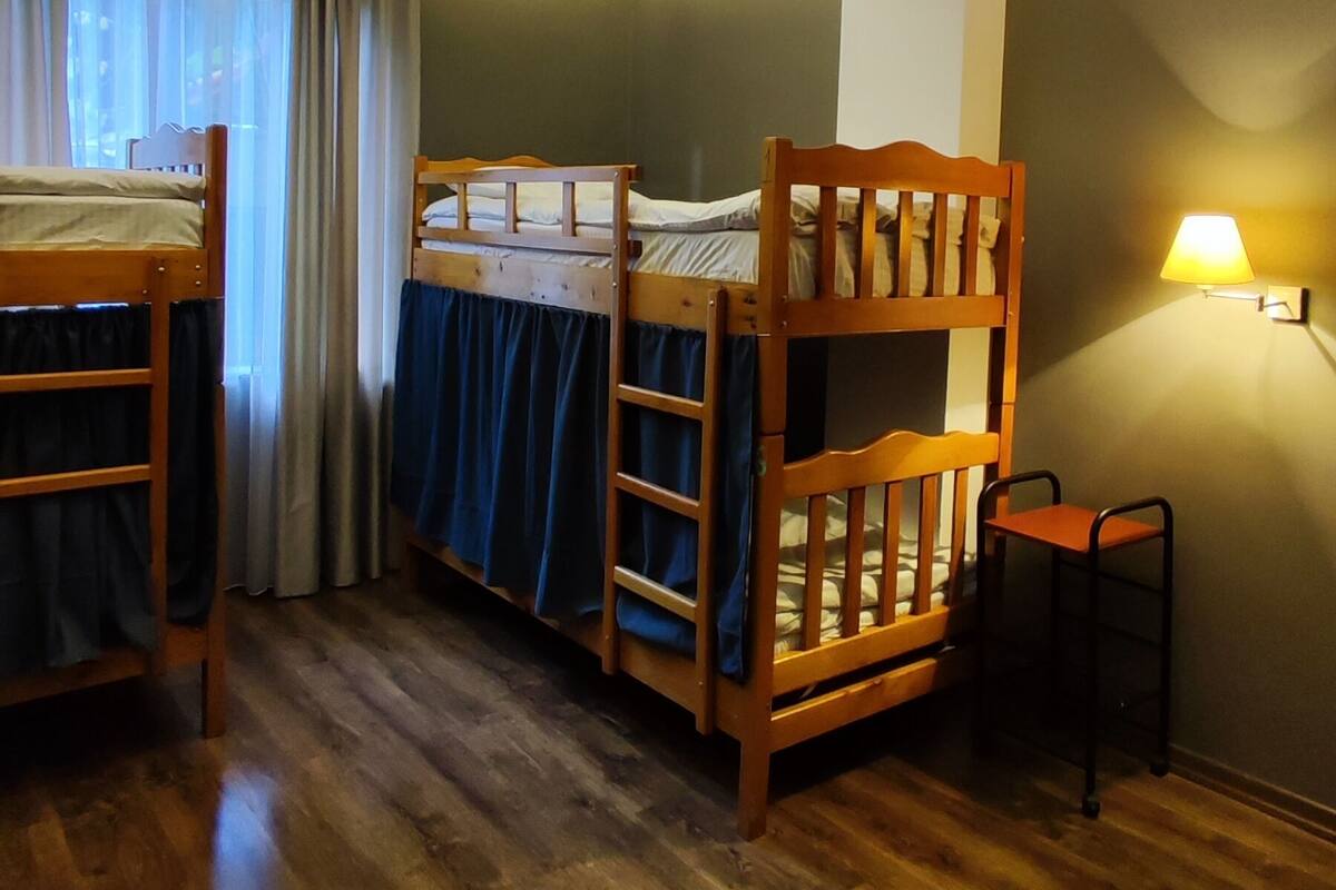 A room with two bunk beds, a desk, and a chair.