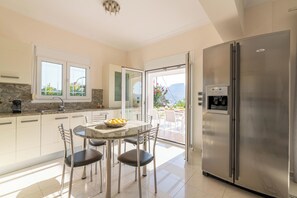 A modern kitchen with a marble countertop, stainless steel appliances, and a dining area with a glass table and chairs.