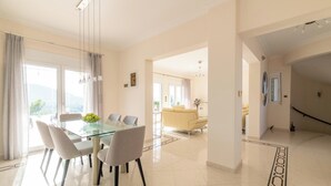 Un espace repas moderne avec une table en verre, des chaises et une vue sur l’extérieur.