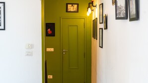 A hallway with a green door, a light switch, a thermostat, and framed pictures on the wall. - Stylish in Spanish Quarter by Wonderful Italy (Napoli)