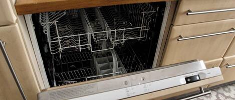 A dishwasher with a control panel, a wooden countertop above it, and a patterned floor.