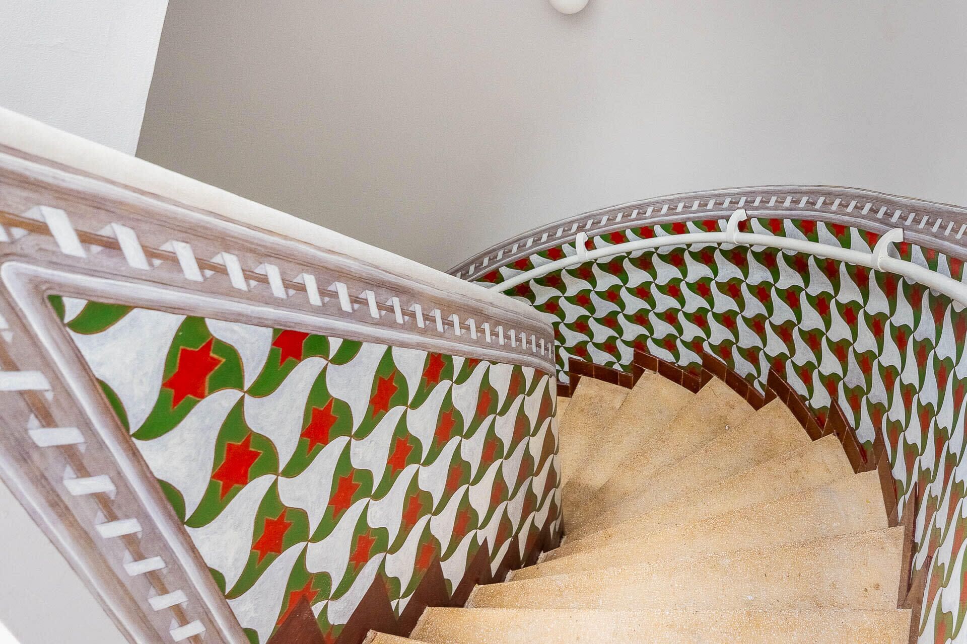 A staircase with a patterned handrail and a beige carpet.