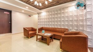 A modern lobby with a wooden ceiling, a large wall-mounted fan, and a seating area with leather sofas and a coffee table. - Metropolis Business Hotel (Panaji)