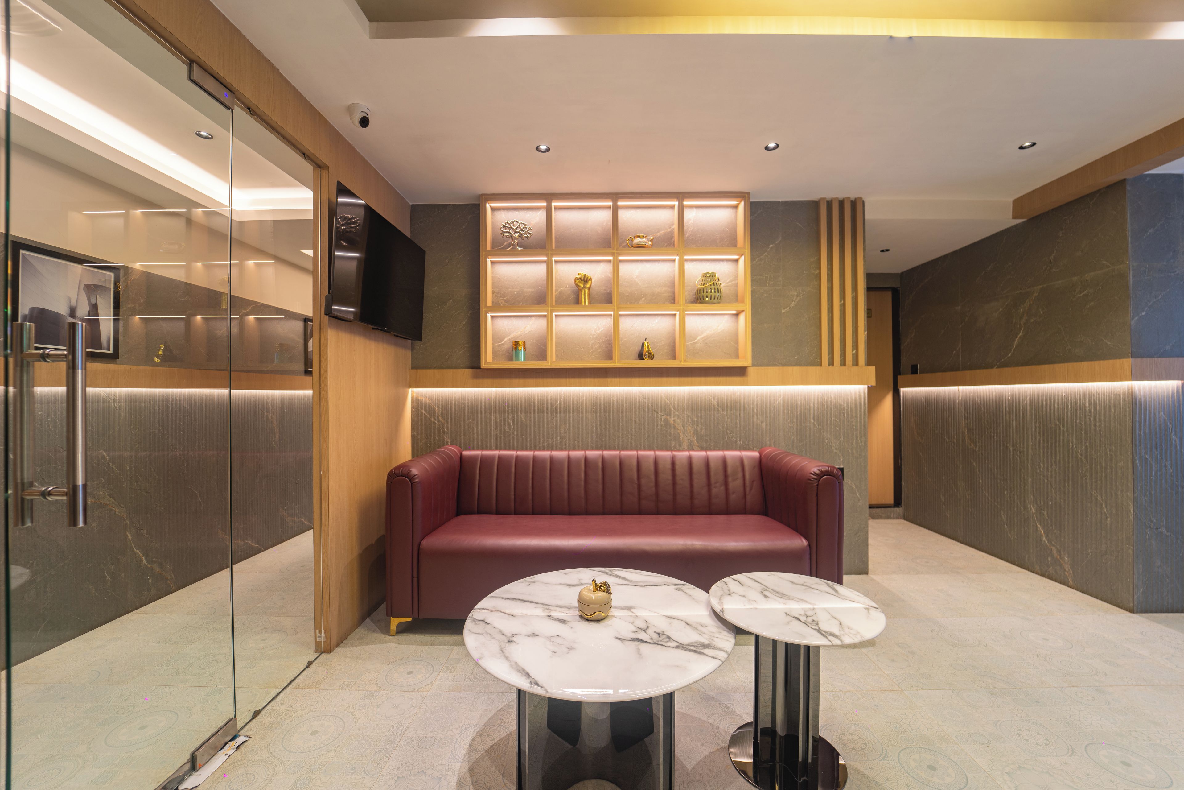 A modern interior with a seating area, marble-topped tables, and a wall-mounted display.