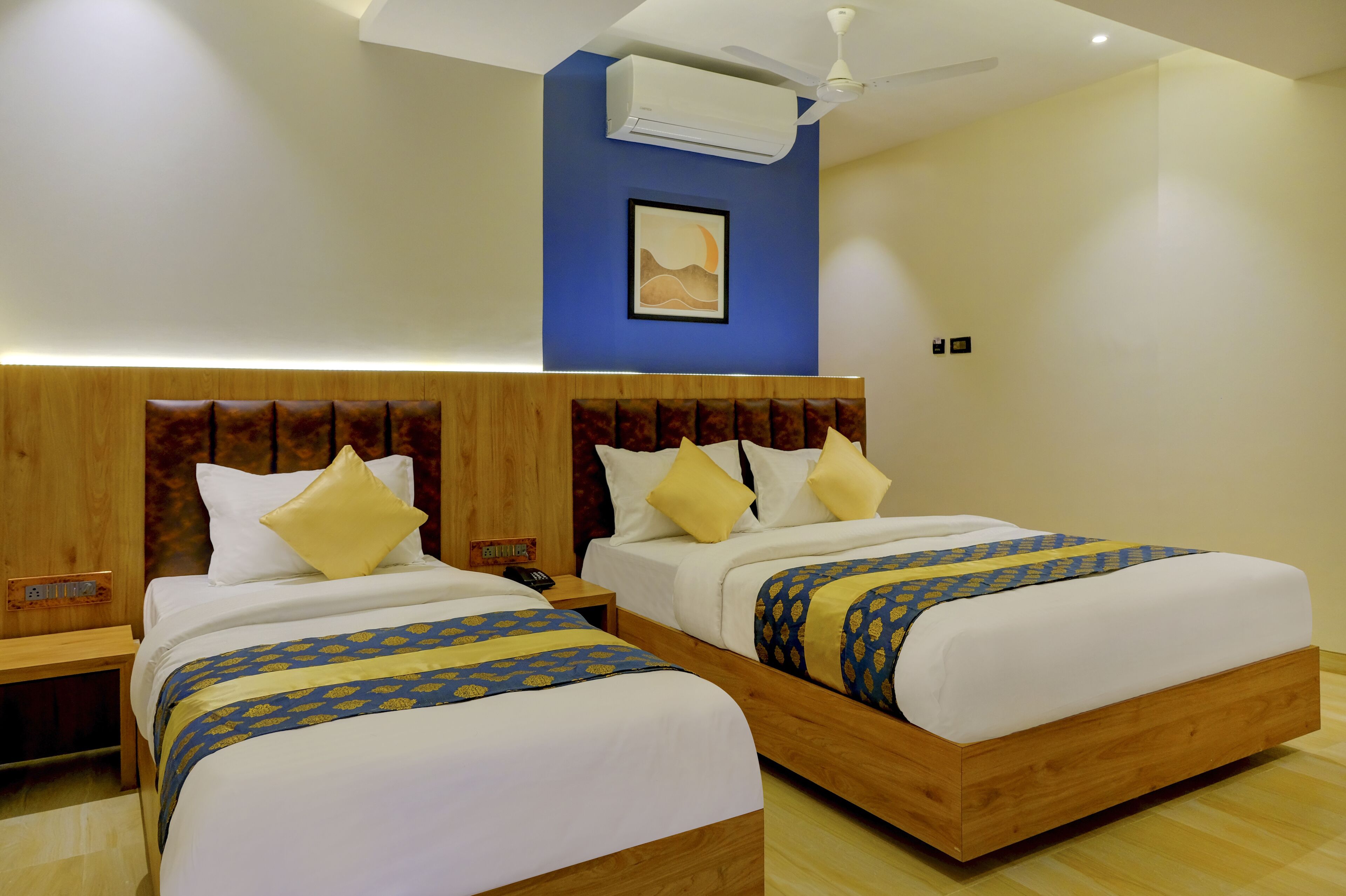 A hotel room with two beds, wooden headboards, and a ceiling fan.