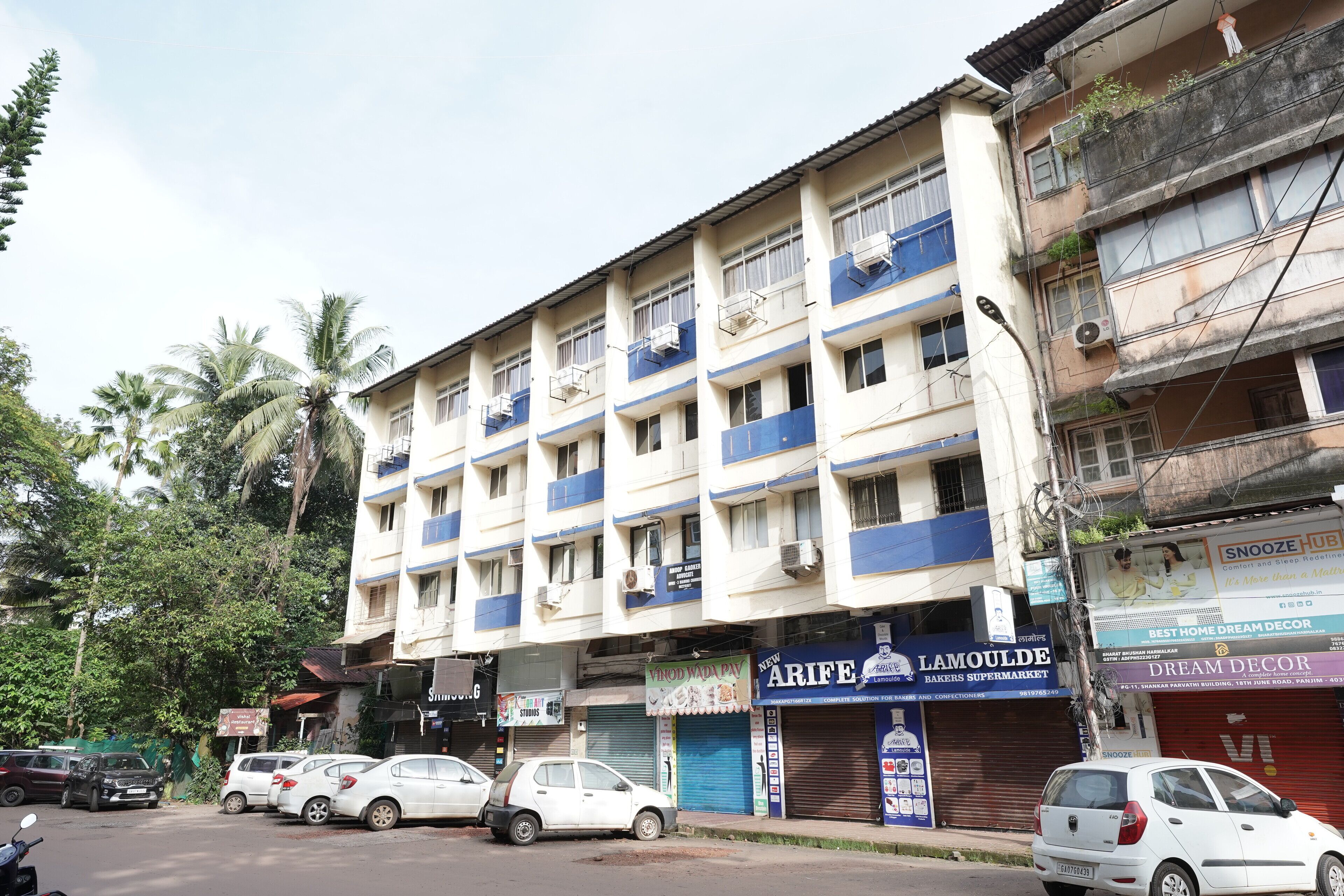A multi-story building with several shops on the ground floor, including a bakery and a home decor store.