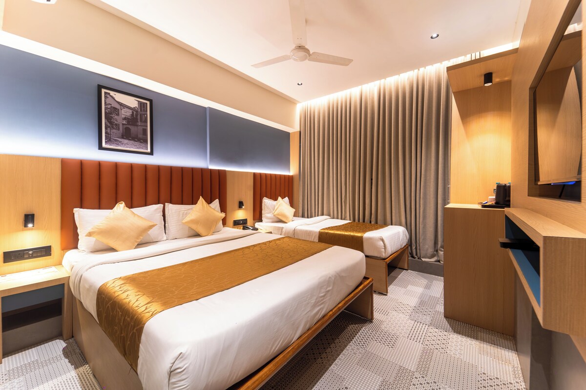 A hotel room with a large bed, two bedside tables, a desk, a chair, a ceiling fan, and a large window with curtains.