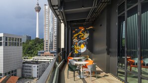 Un balcon avec vue sur la ville, des chaises modernes et une fresque murale.