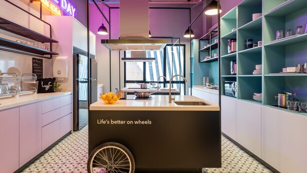 Une cuisine moderne dotée d’un îlot central, d’un néon et d’un aménagement conçu pour être accessible aux personnes en fauteuil roulant.