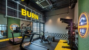 Une salle de sport équipée de tapis de course, de vélos d’exercice et d’un banc de musculation.