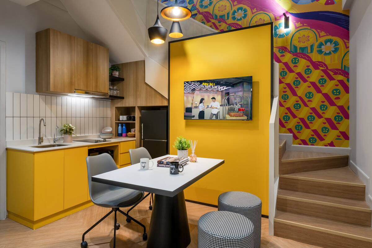 A modern kitchen with yellow cabinets, a white countertop, and a dining area with a table and chairs.