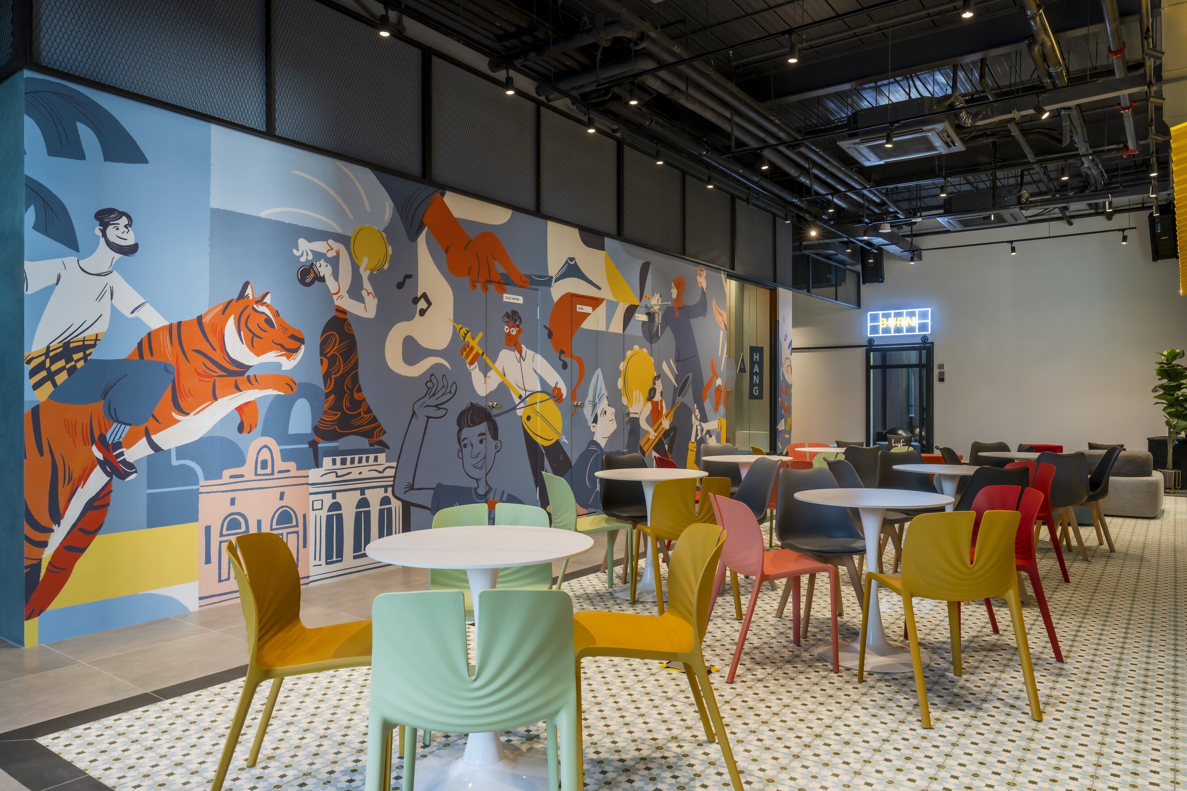 A modern cafe with colorful chairs and tables, a mural with various characters, and a visible sign that reads "HANG".
