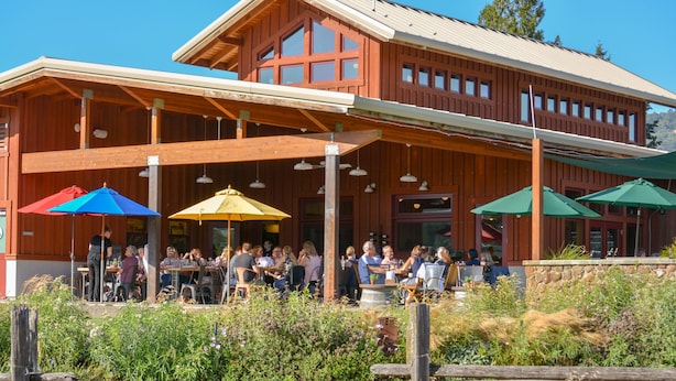 Een houten gebouw met terras en parasols.