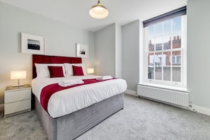 Relax in a spacious room with a large bed, bedside table, and city view.
